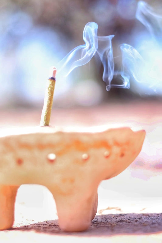 Close-up of a handcrafted incense stick in a traditional copaler, set against the golden tones of the desert, perfect for earthing and meditation
