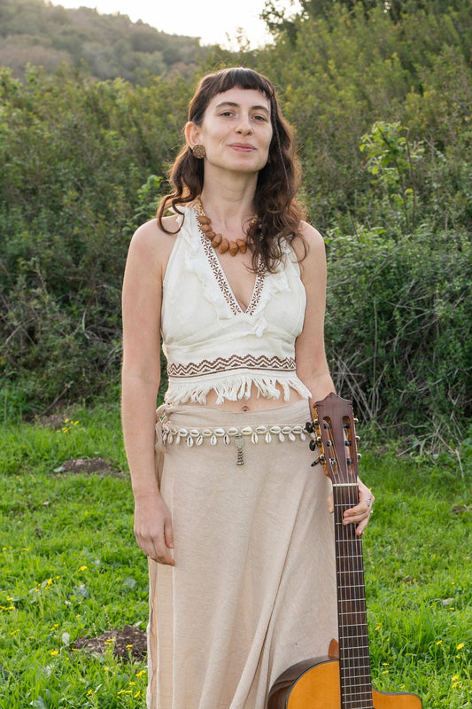 Woman wearing a natural handwoven khadi cotton halter top with deep V-neck and tribal block print, styled outdoors in a green field