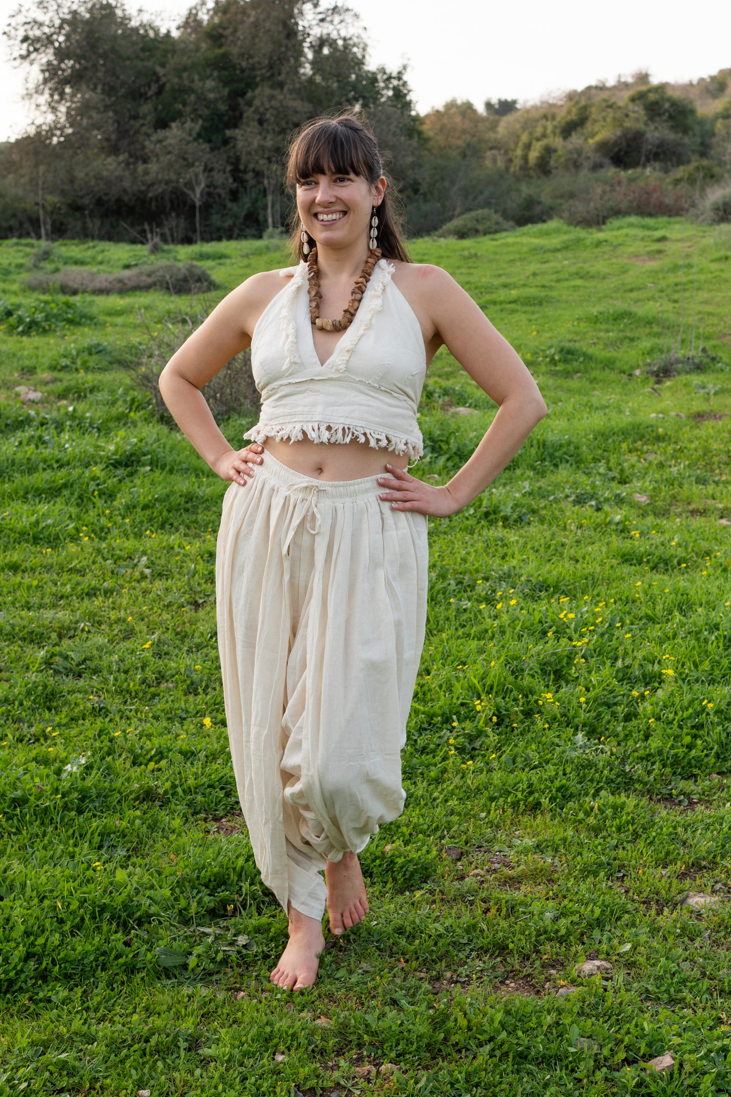 Woman wearing a natural khadi cotton halter top with frayed edges, styled outdoors in a green field