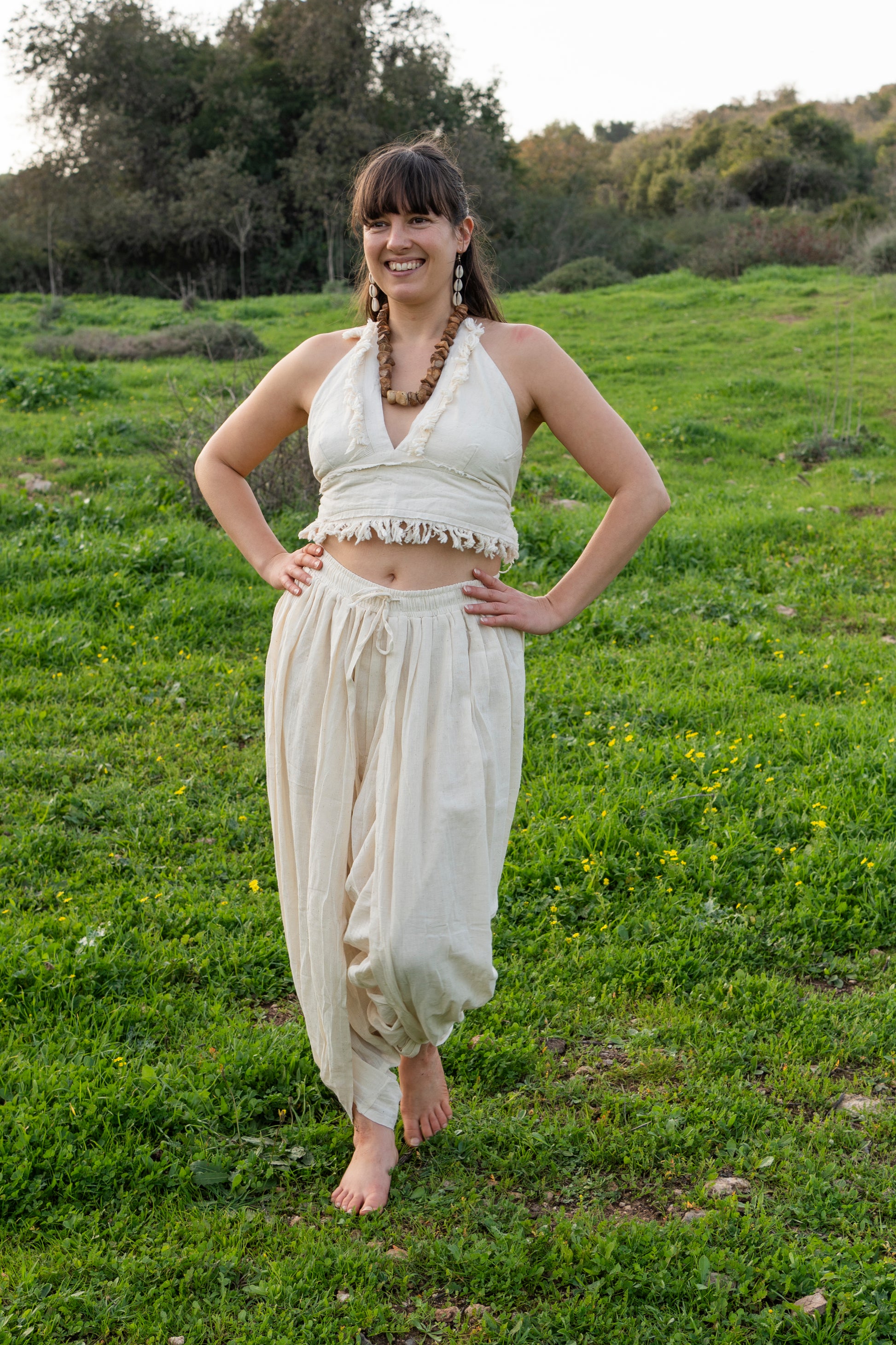 Woman wearing a natural khadi cotton halter top with frayed edges, styled outdoors in a green field