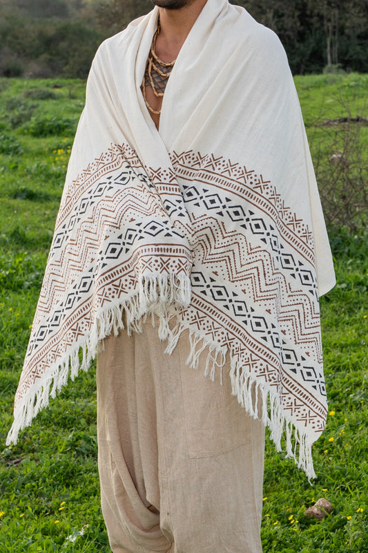Person wearing a natural khadi cotton shawl wrapped around the shoulders, featuring tribal prints and fringes in an outdoor landscape.