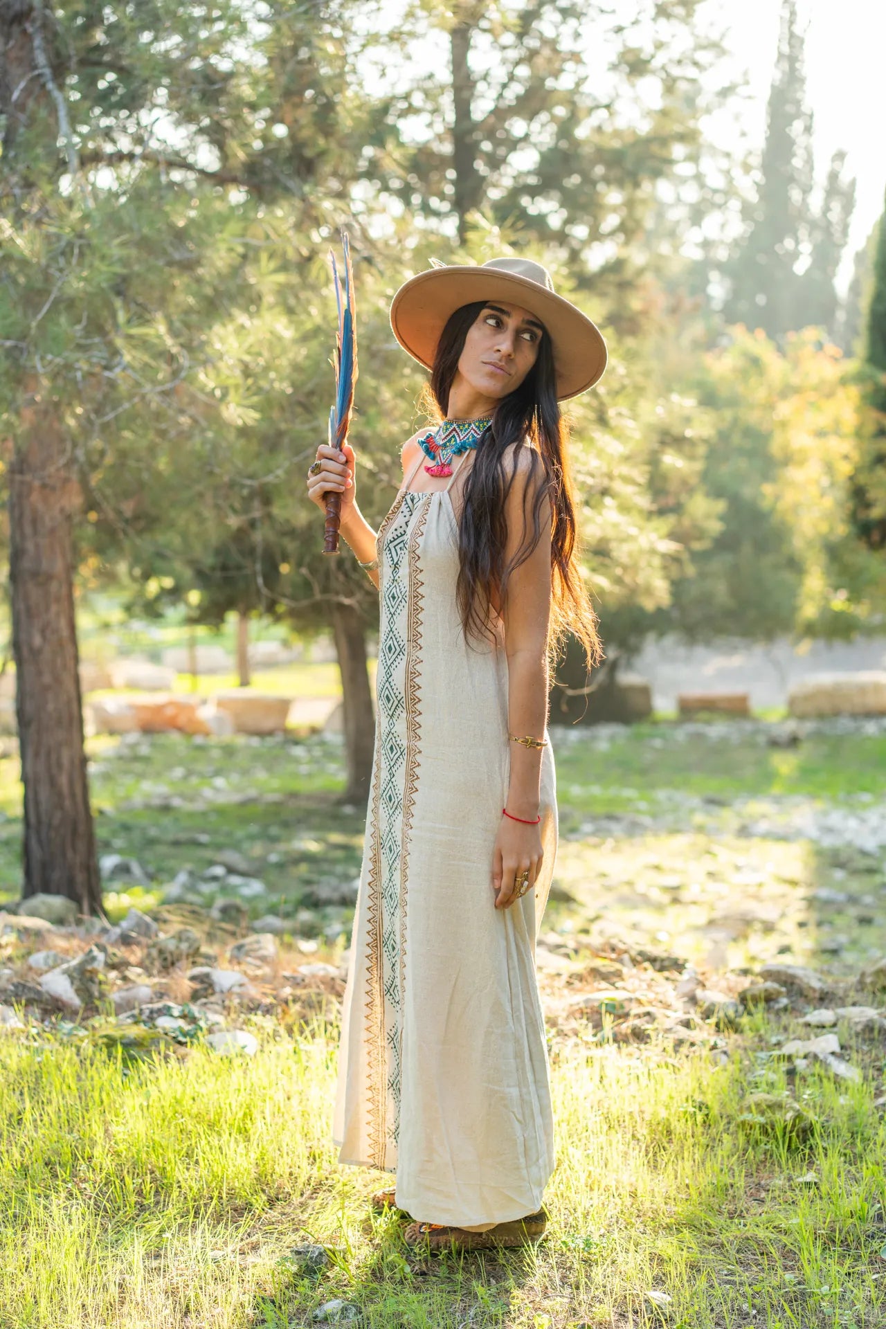 Side profile of a woman in a tribal print cotton dress with an open back design, showcasing the elegant silhouette and movement of the fabric in nature.