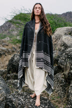 Woman wearing black handloom organic cotton tribal shawl styled as a wrap in a natural outdoor setting