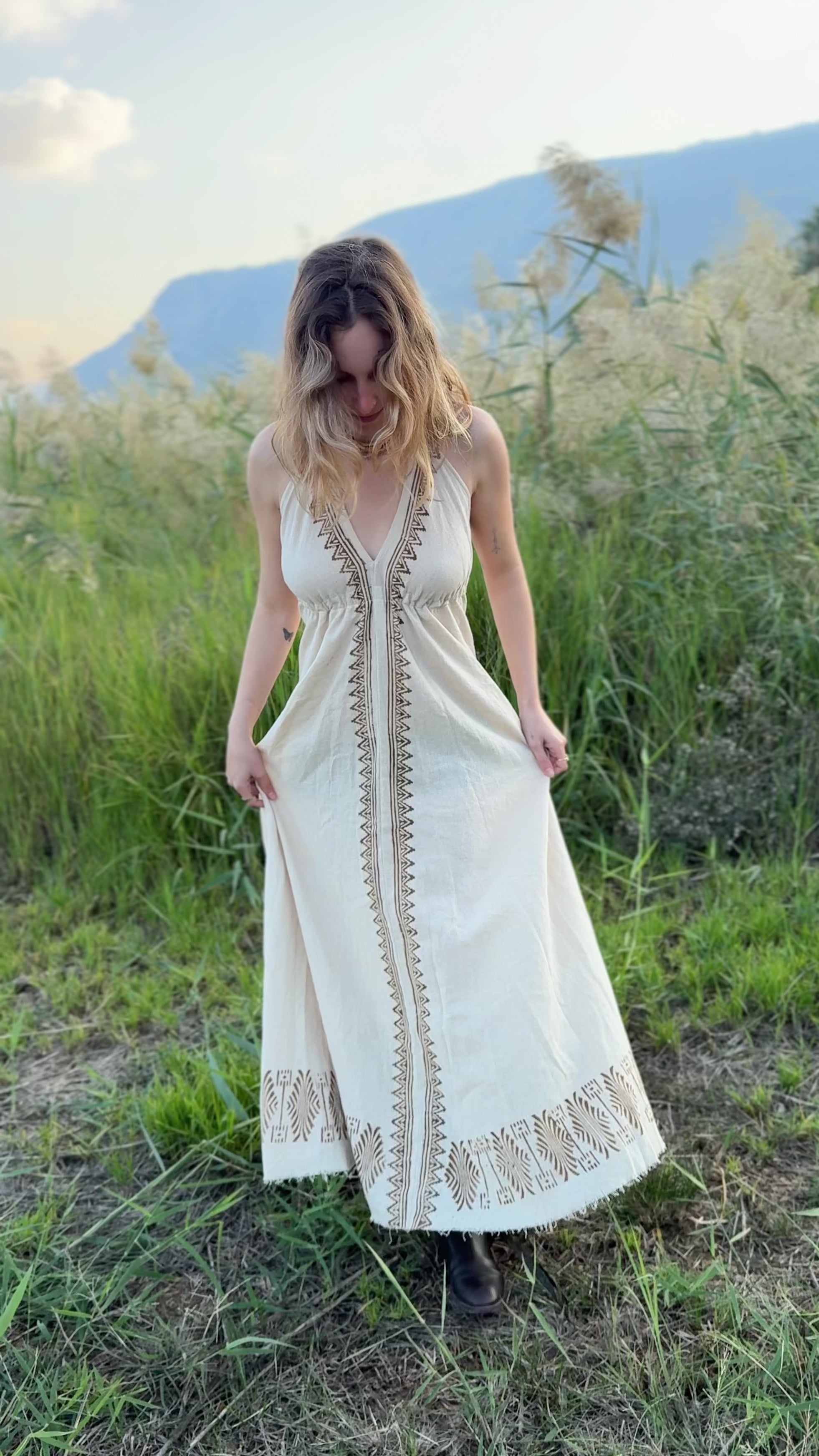 Video showing the fit and flow of the Naya long butterfly dress - a natural cotton maxi dress with block print details - filmed outdoors.
