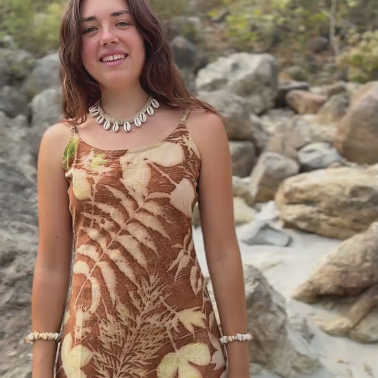 Woman wearing earthy short botanical dye dress with leaf prints. Eco-friendly slow fashion