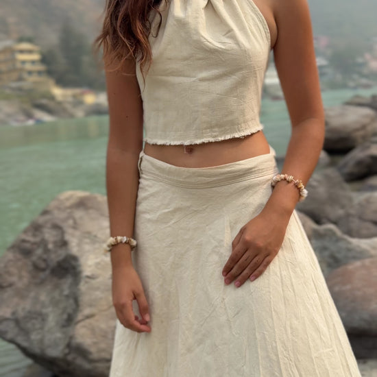 Woman outdoors in nature wearing a flowy white khadi cotton wrap skirt and crop top.