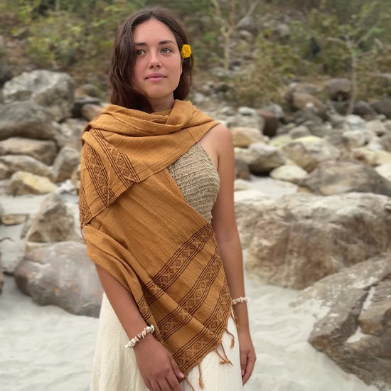 Short video of a smiling woman in nature wearing a brown handwoven cotton scarf with tribal wooden block prints.