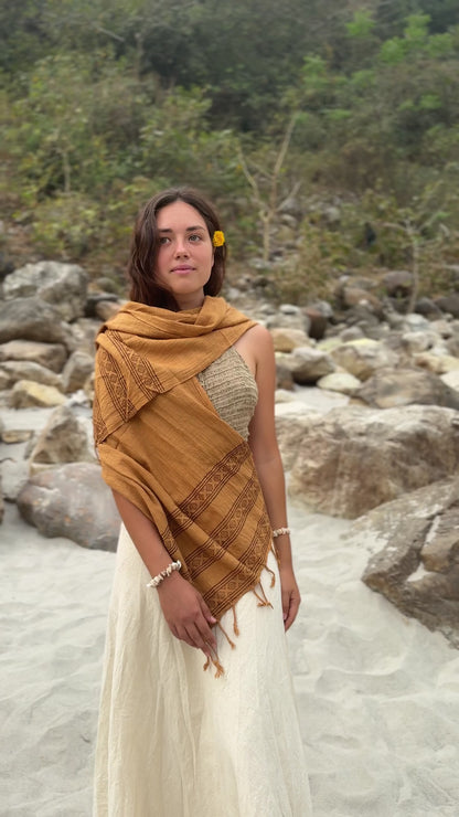 Short video of a smiling woman in nature wearing a brown handwoven cotton scarf with tribal wooden block prints.