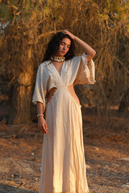 Woman in a white raw silk dress with a priestess, fairy dress feel, standing in warm sunlight.