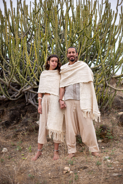 Couple wearing raw khadi cotton shawls, standing barefoot in a desert landscape.