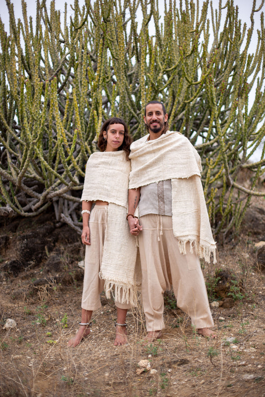 Couple wearing raw khadi cotton shawls, standing barefoot in a desert landscape.