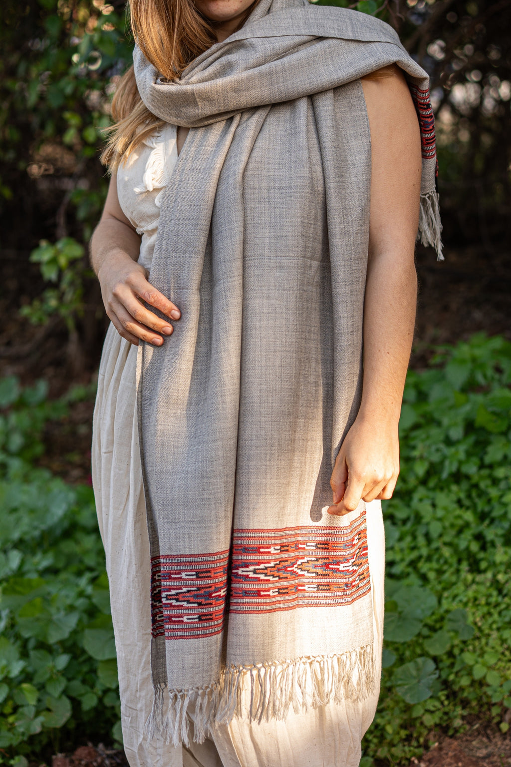 Light grey handwoven wool shawl featuring a traditional red and black geometric Kullu border. Authentic Indian tribal fashion for winter warmth