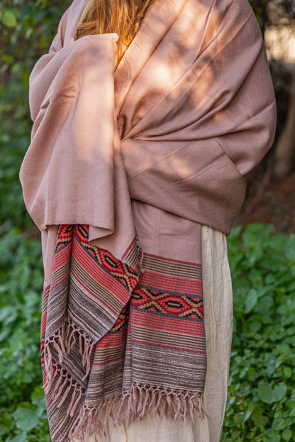 Dusty pink wool wrap with a classic red and black geometric woven border. Soft, handloom ethnic shawl styled for a rustic bohemian look.