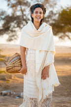 Cream handwoven natural wool shawl styled as a warm wrap on a model outdoors