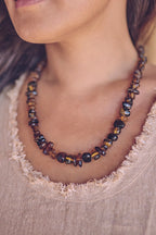 A Woman wearing a dark amber necklace with adjustable size and hand polished finish.